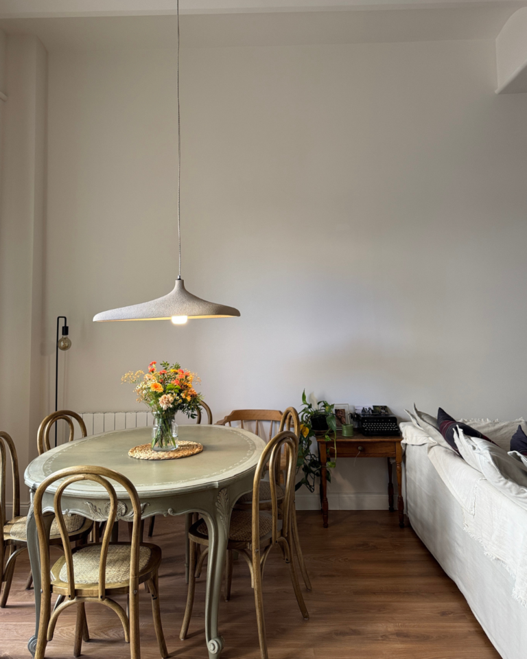 Comedor de la reforma Roses en Esplugues, con mesa redonda, lámpara colgante y suelo laminado de madera